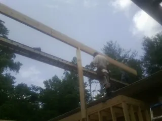 Carpenter setting a ridge beam over a new addition frame — Ice Dam Removal by Roofing Brothers in Bertram