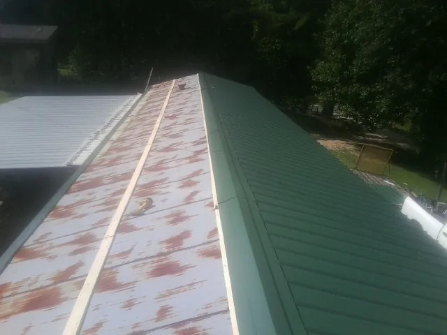 Old rusted panels beside newly installed green metal roofing — Wind Damage Roof Repair by Roofing Brothers in Bertram