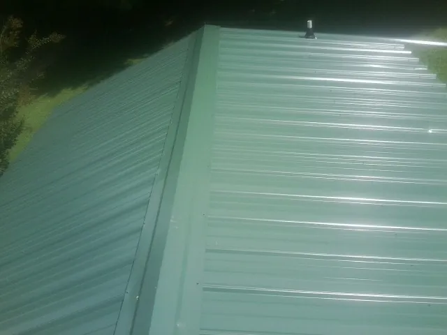 New green metal panels meeting at the ridge of a roof — Flat Roof Repair work by our crew in Bertram