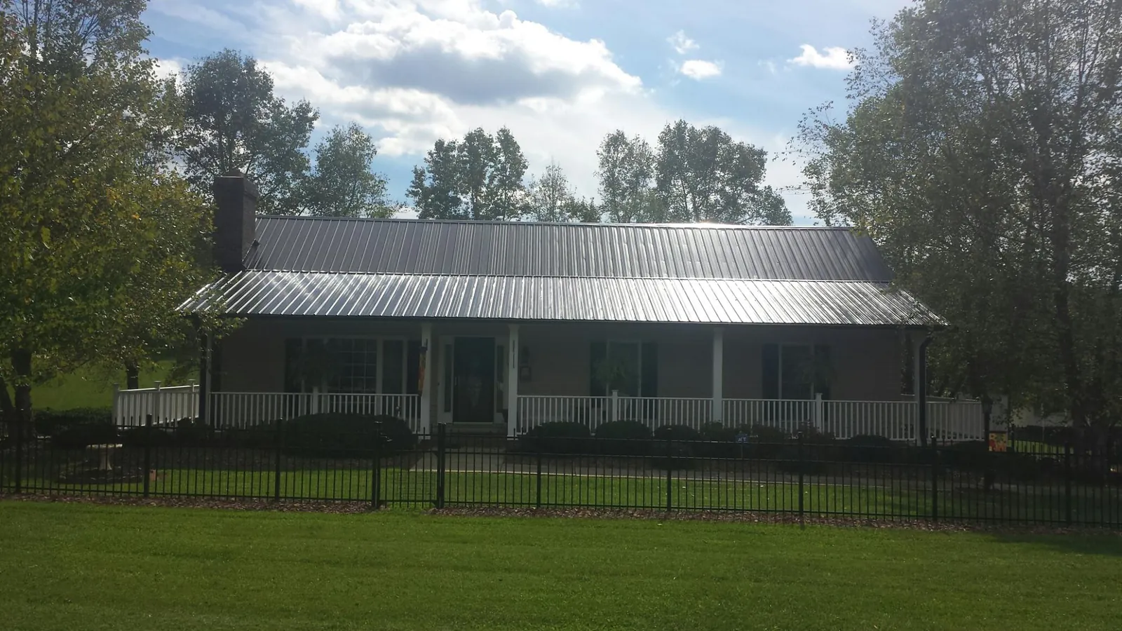 Gray metal roof on a brick ranch with a full width front porch — Gutter Guard Installation work by our crew in Bertram